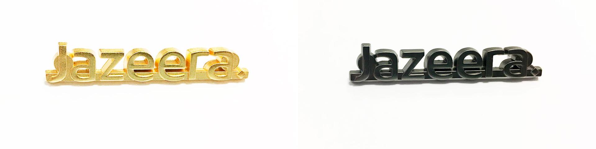 A gold-colored pin and a black pin for Jazeera Airways